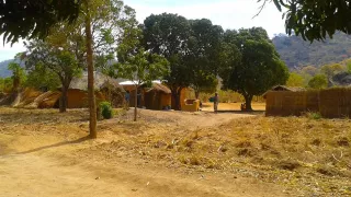 Ländliche Region in Malawi mit mehreren Lehmhäusern und Feldern.