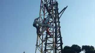 Zwei Personen, die an einem Mast hängen.
